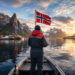 Angler in einem Boot auf einem norwegischen Fjord mit norwegischer Flagge vor beeindruckender Bergkulisse – Titelbild zum Ratgeber über die neuen Bestimmungen für das Angeln in Norwegen.