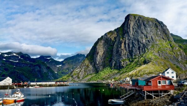 Beeindruckender norwegischer Fjord mit Angelbooten, roten Holzhäusern und steilen Bergen – beliebtes Reiseziel für Angler.