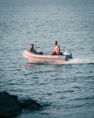 Ein Mann fährt allein mit einem motorisierten Schlauchboot über einen See.