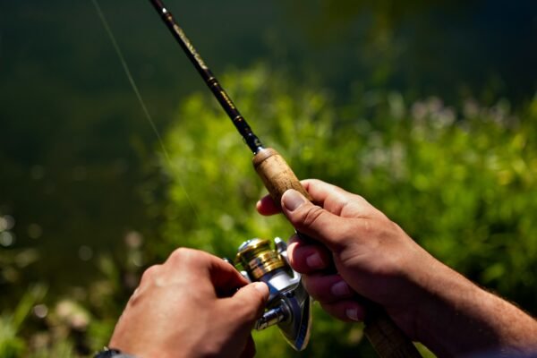 Angler hält eine ultraleichte Spinnrute mit kleiner Stationärrolle in der Hand