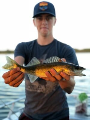Angler präsentiert einen frisch gefangenen Zander am Gewässer – erfolgreicher Fang beim Zanderangeln im Winter.