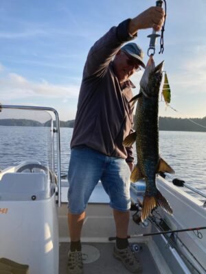 Angler präsentiert einen großen Hecht auf einem Boot