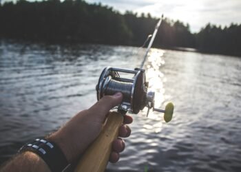Angler hält eine Bootsrute mit Multirolle über dem Wasser