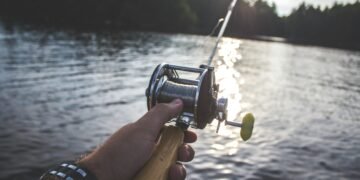 Angler hält eine Bootsrute mit Multirolle über dem Wasser