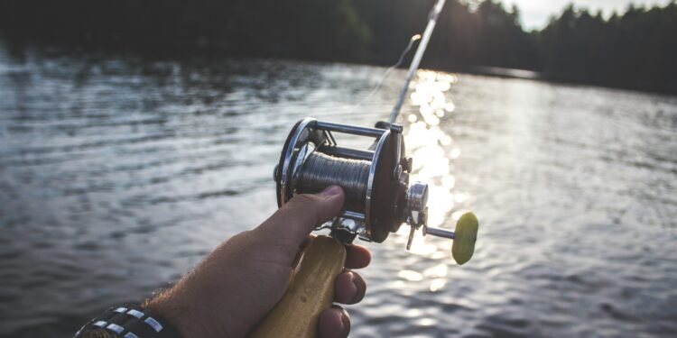 Angler hält eine Bootsrute mit Multirolle über dem Wasser
