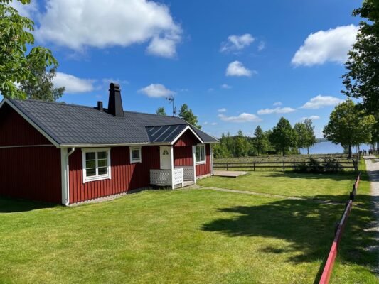 Rotes skandinavisches Ferienhaus mit Garten direkt an einem See