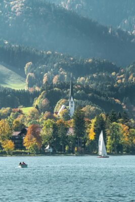 Kleines Boot und Segelboot auf dem Tegernsee vor bewaldeten Bergen