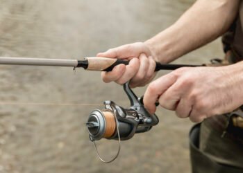 Angler hält eine Rute mit bespulter Rolle am Wasser und testet eine Karpfenschnur
