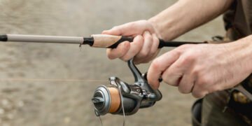 Angler hält eine Rute mit bespulter Rolle am Wasser und testet eine Karpfenschnur