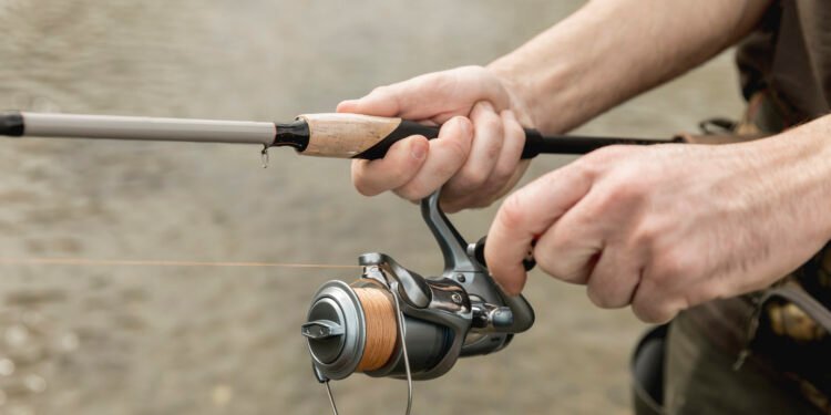 Angler hält eine Rute mit bespulter Rolle am Wasser und testet eine Karpfenschnur