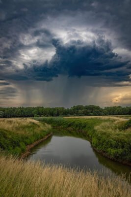 Kräftige Gewitterwolken mit Regen über einem kleinen Fluss