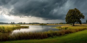 Dunkle Gewitterfront mit Starkregen über einem See und einer Uferlandschaft