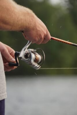 Nahaufnahme eines Anglers beim Einholen einer leichten Spoonrute mit Stationärrolle