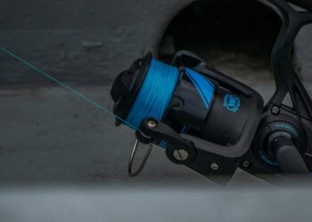 Nahaufnahme einer schwarzen Stationärrolle mit blauer Angelschnur auf der Spule.