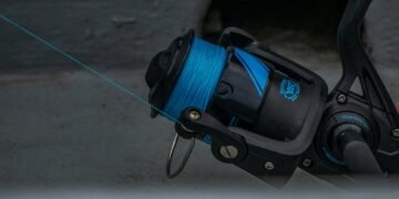 Nahaufnahme einer schwarzen Stationärrolle mit blauer Angelschnur auf der Spule.