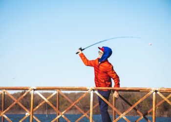 Junger Angler wirft eine leichte Spoon Angelrute von einem Steg aus