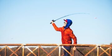Junger Angler wirft eine leichte Spoon Angelrute von einem Steg aus
